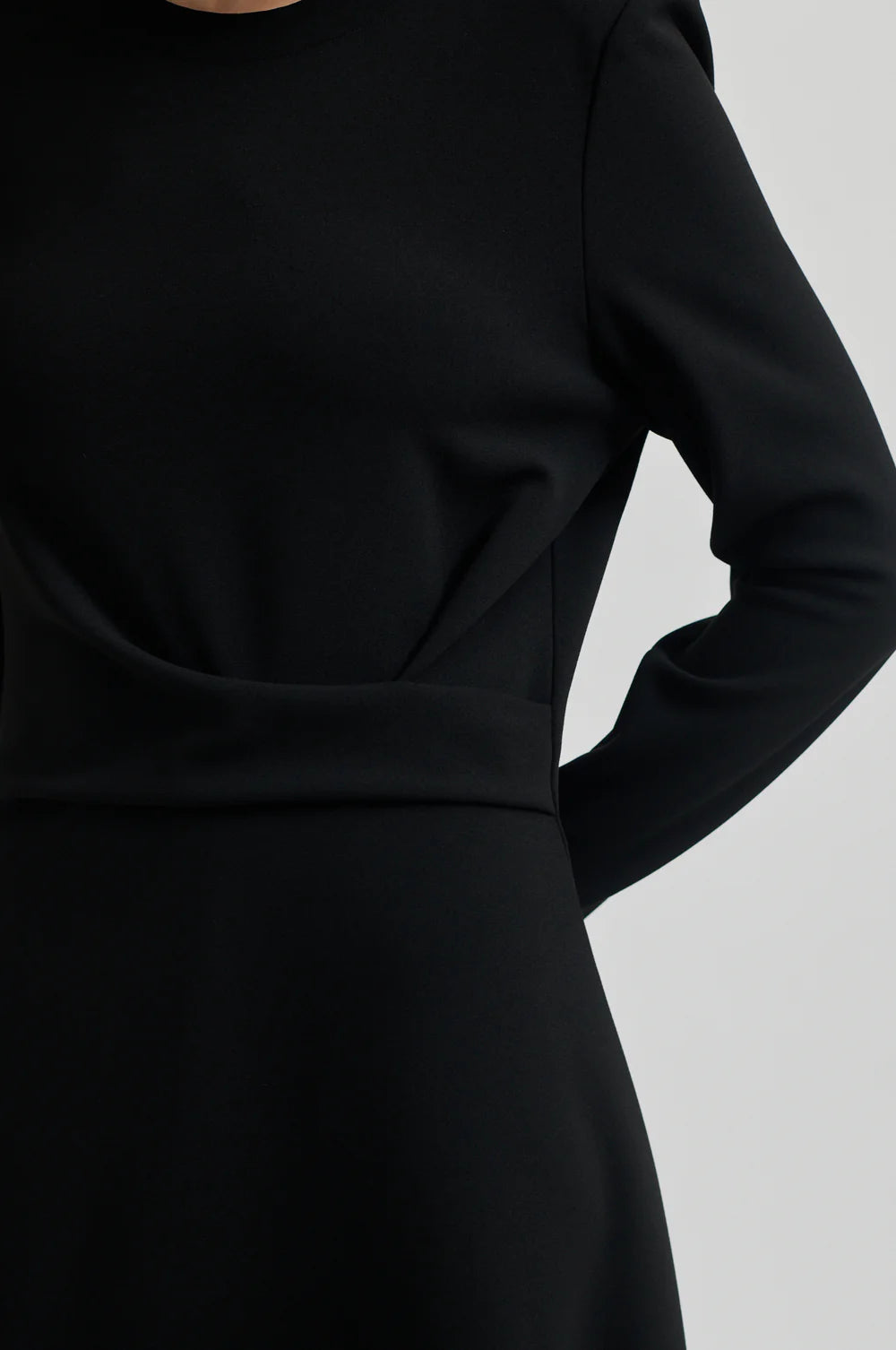 Black long sleeve dress with pleated details at one side that create a flattering draped effect. Front slit. 