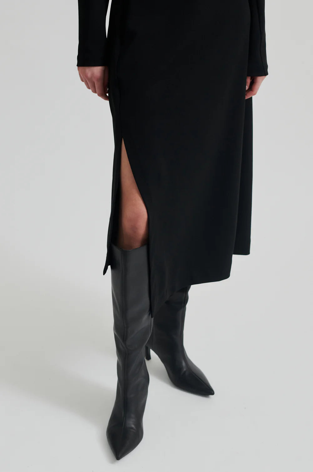 Black long sleeve dress with pleated details at one side that create a flattering draped effect. Front slit. 