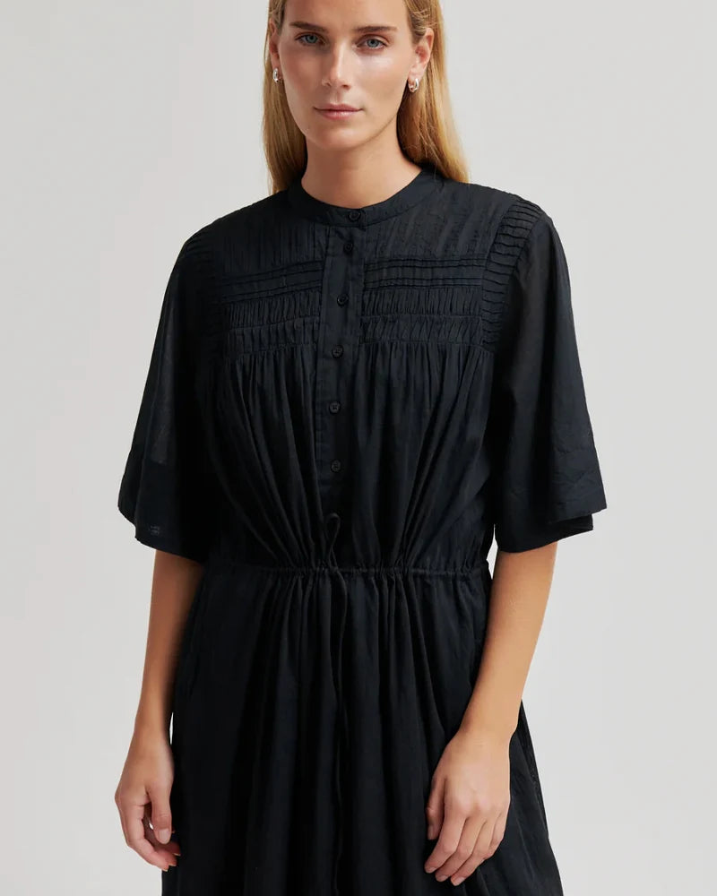 Woman wearing a black dress against a plain background