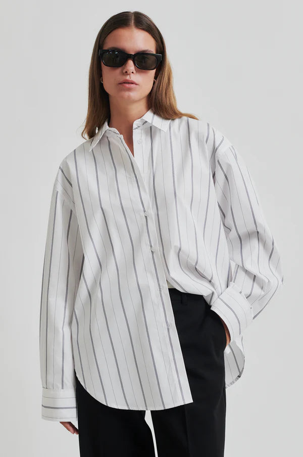 White cotton shirt with black vertical stripes. Long sleeve and oversize fit. 