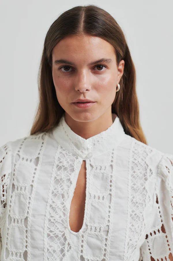 Model wearing broderie long sleeve off white blouse paired with soft grey denim jeans. 