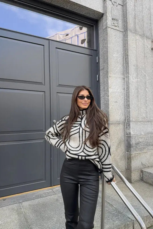 Woman in a black and white striped sweater standing in front of a large gray door.