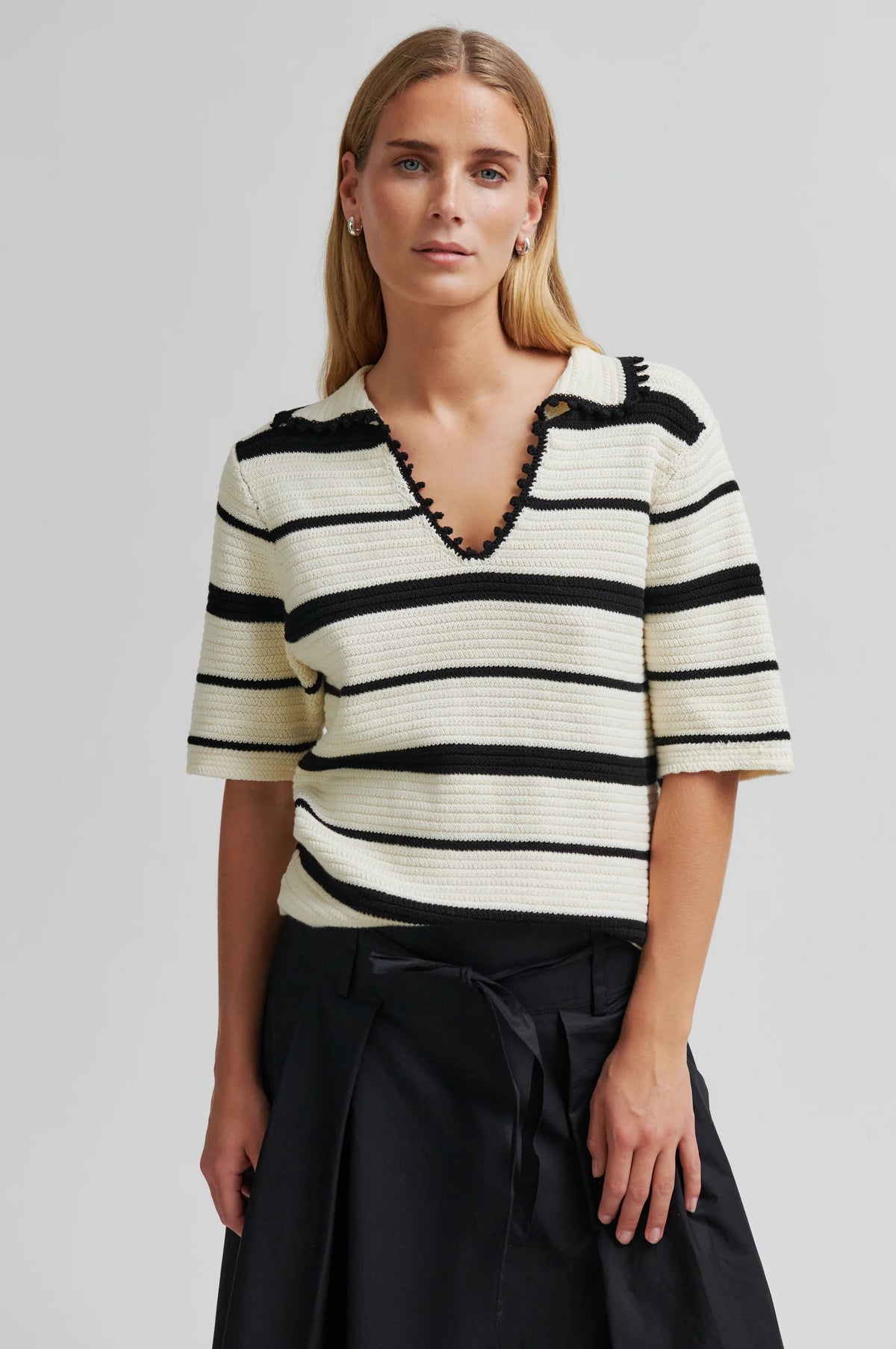 Woman wearing a black and white striped shirt with a plain background