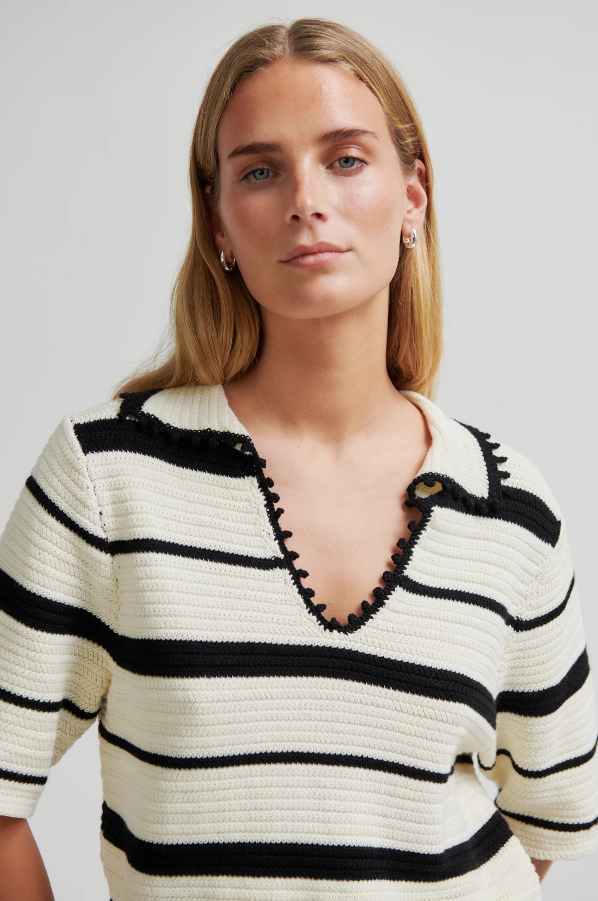 Woman wearing a black and white striped sweater against a plain background