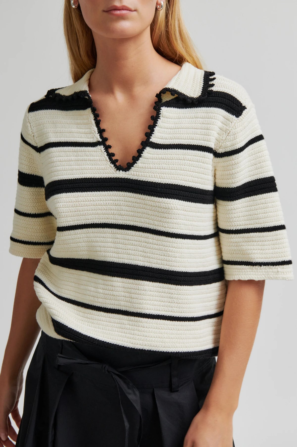 Woman wearing a black and white striped sweater with a plain background