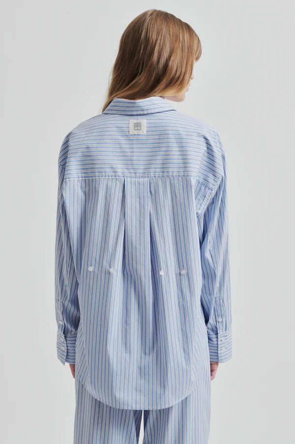 Model wearing a blue and white striped shirt back view. 