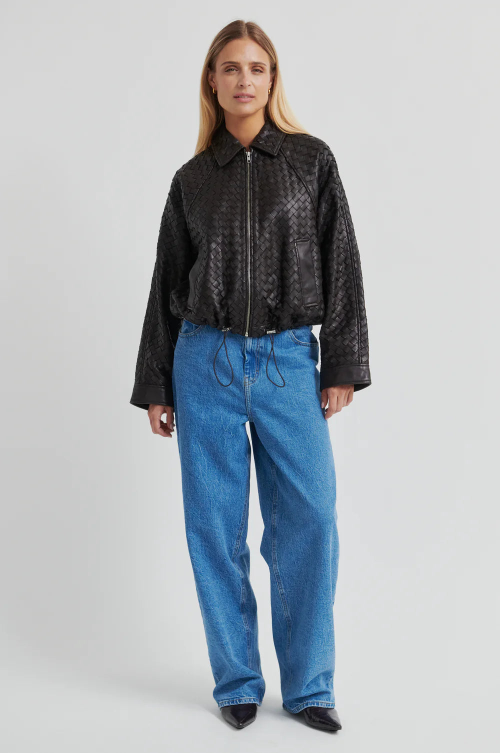 Model wearing a Chocolate Brown woven leather jacket and denim jeans with brown heels on a light background