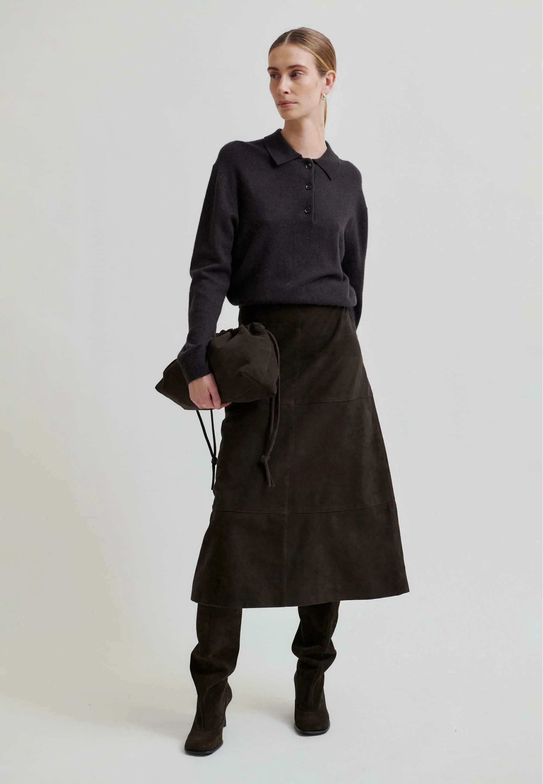 Woman wearing a chocolate brown ribbed sweater with with a long skirt on a white background