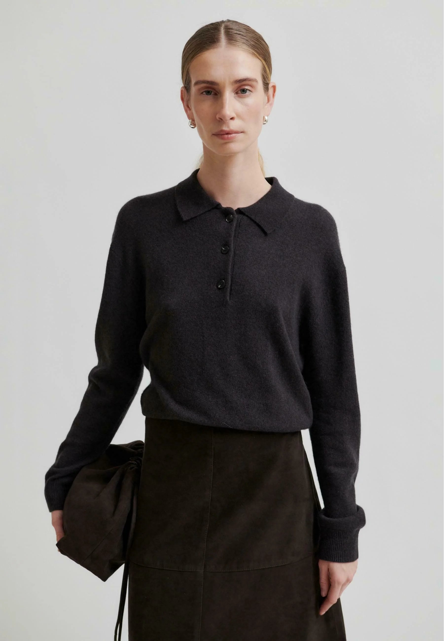 Woman wearing a chocolate brown ribbed sweater with with a long skirt on a white background