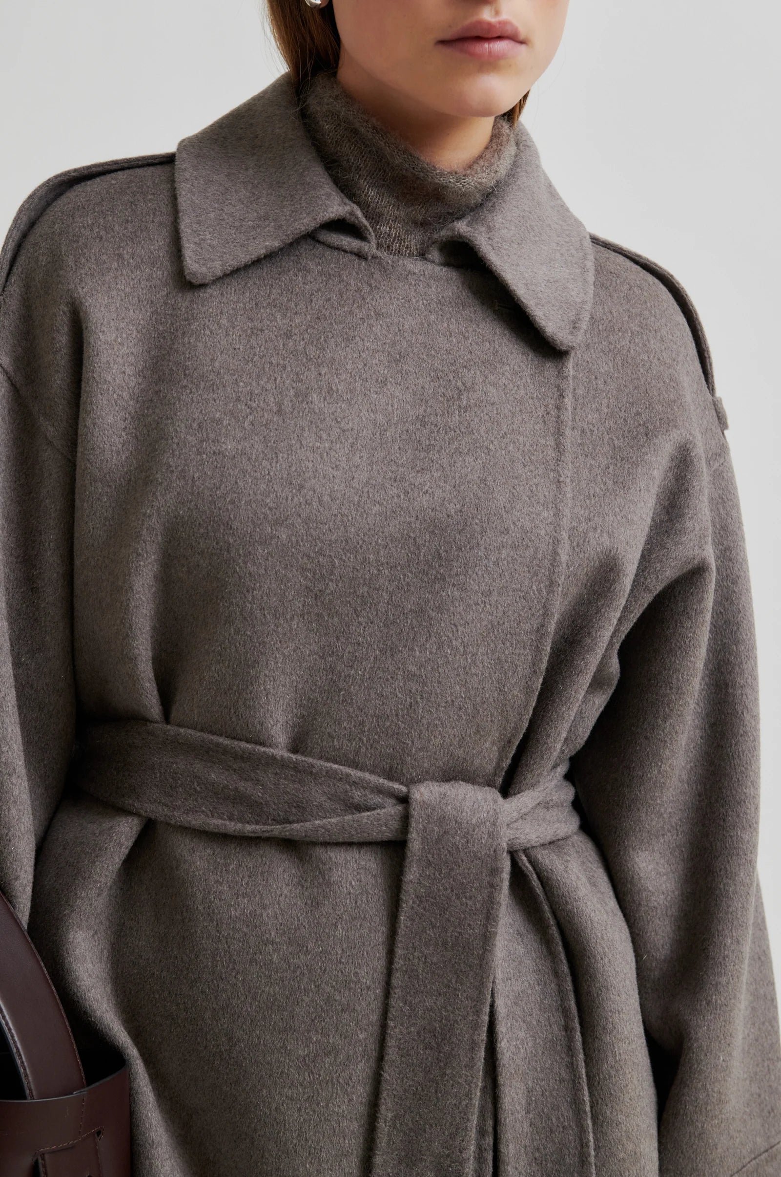 Light brown coat with a belt on a plain background