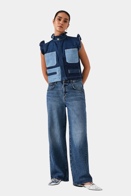 Person wearing a denim vest and jeans on a white background