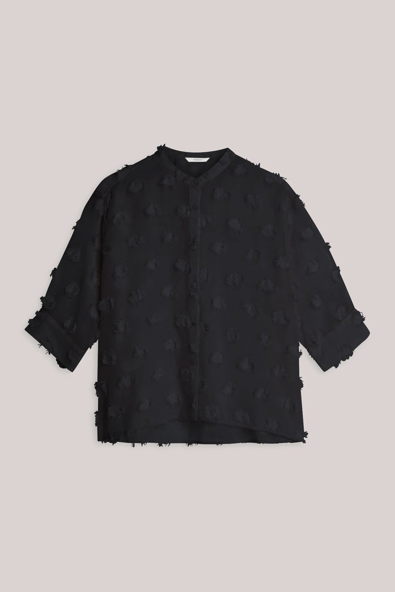 A black textured three-quarter sleeve blouse with round neckline and 3 d printed details  laid flat against a solid light background.
