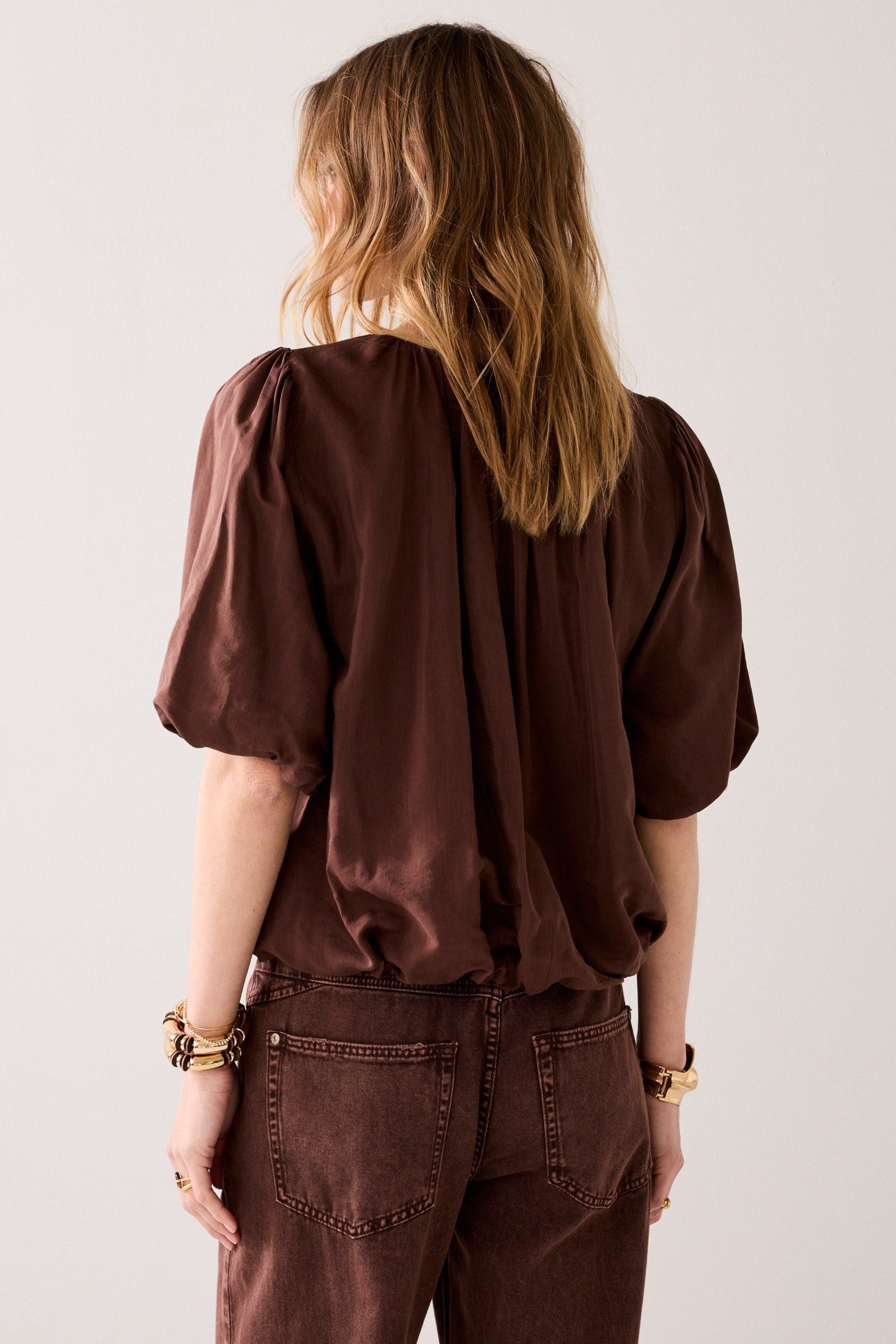 Women shown from the back wearing a brown blouse with short ballon sleeves on a light background