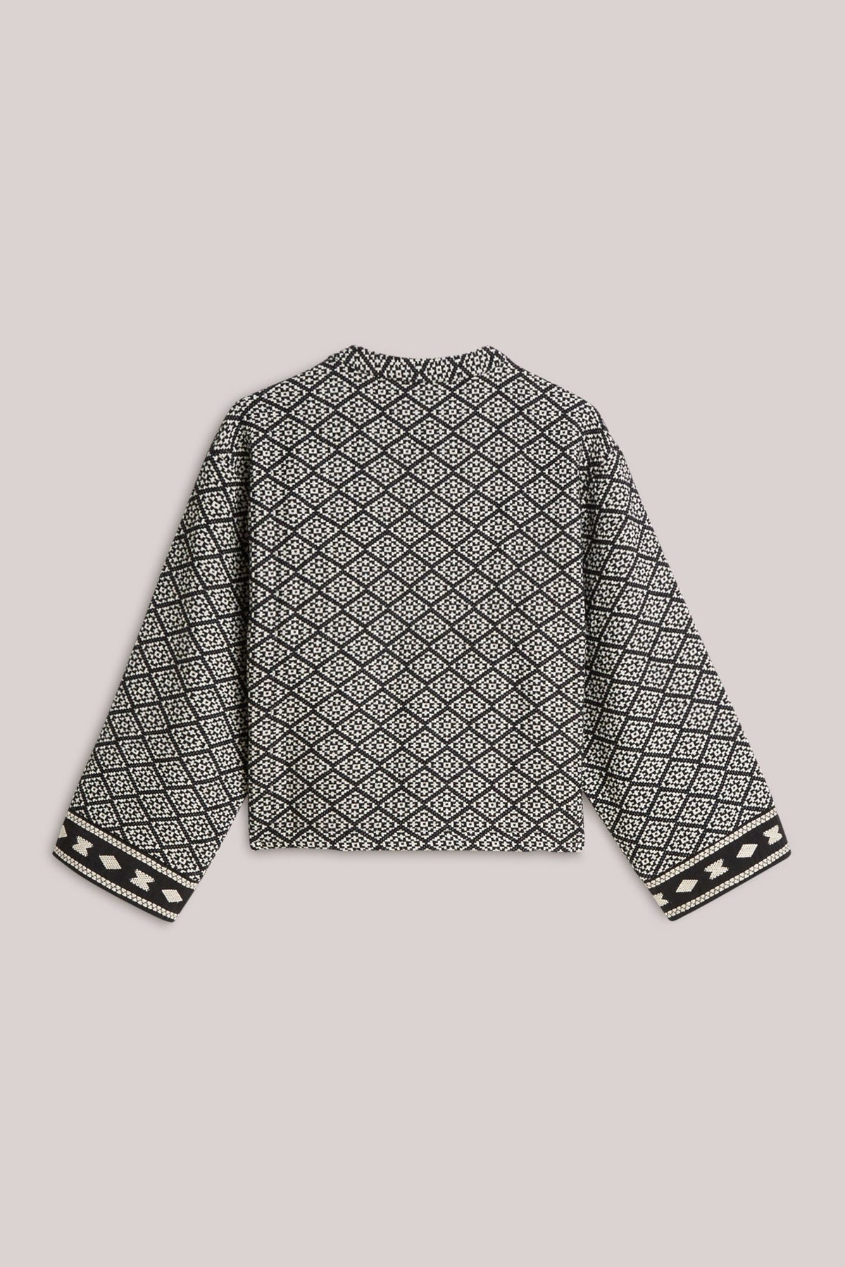 A cropped jacket with a geometric tribal pattern in black and cream, featuring long sleeves and a crew neck, laid flat on a light  background.