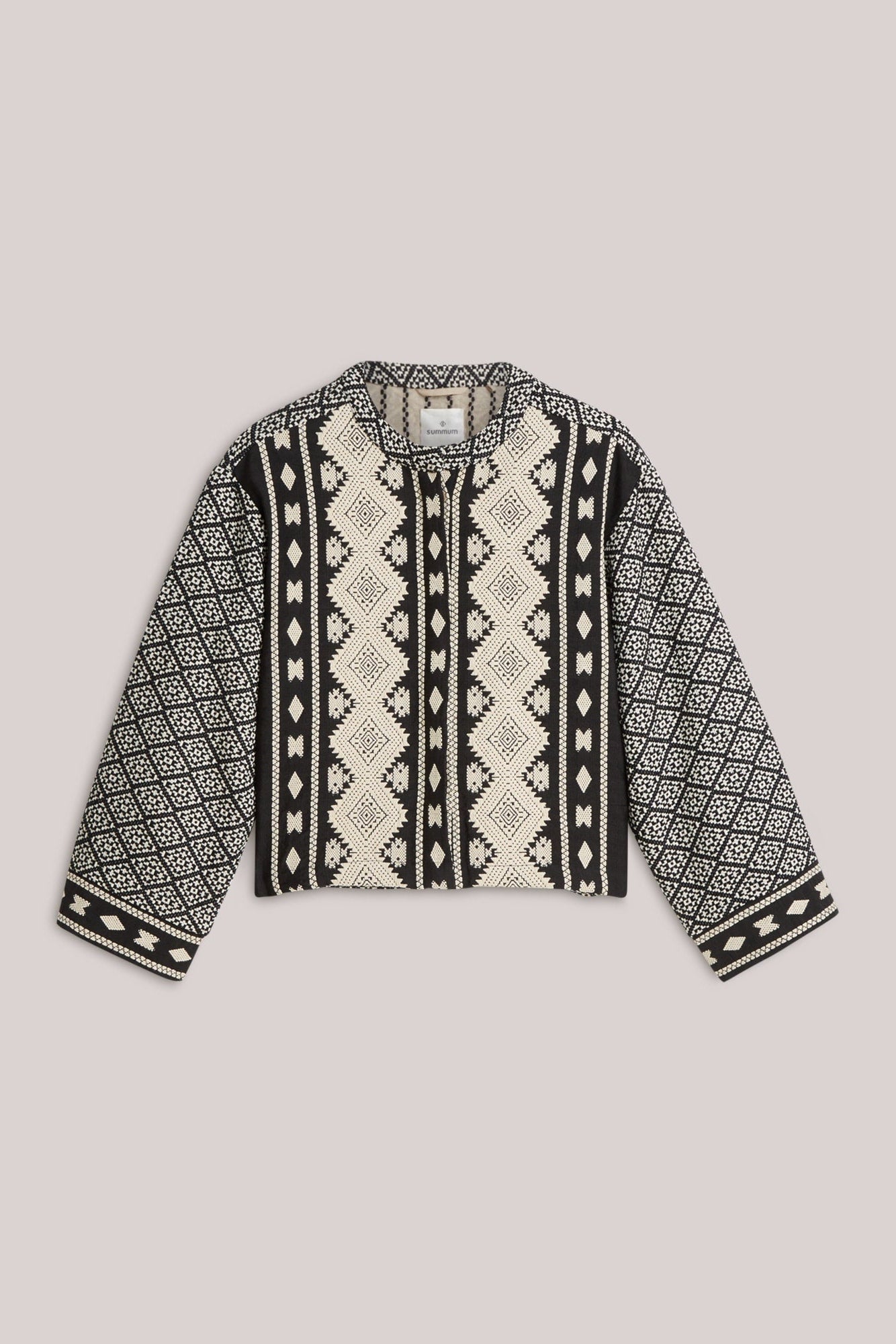 A cropped jacket with a geometric tribal pattern in black and cream, featuring long sleeves and a crew neck, laid flat on a light  background.