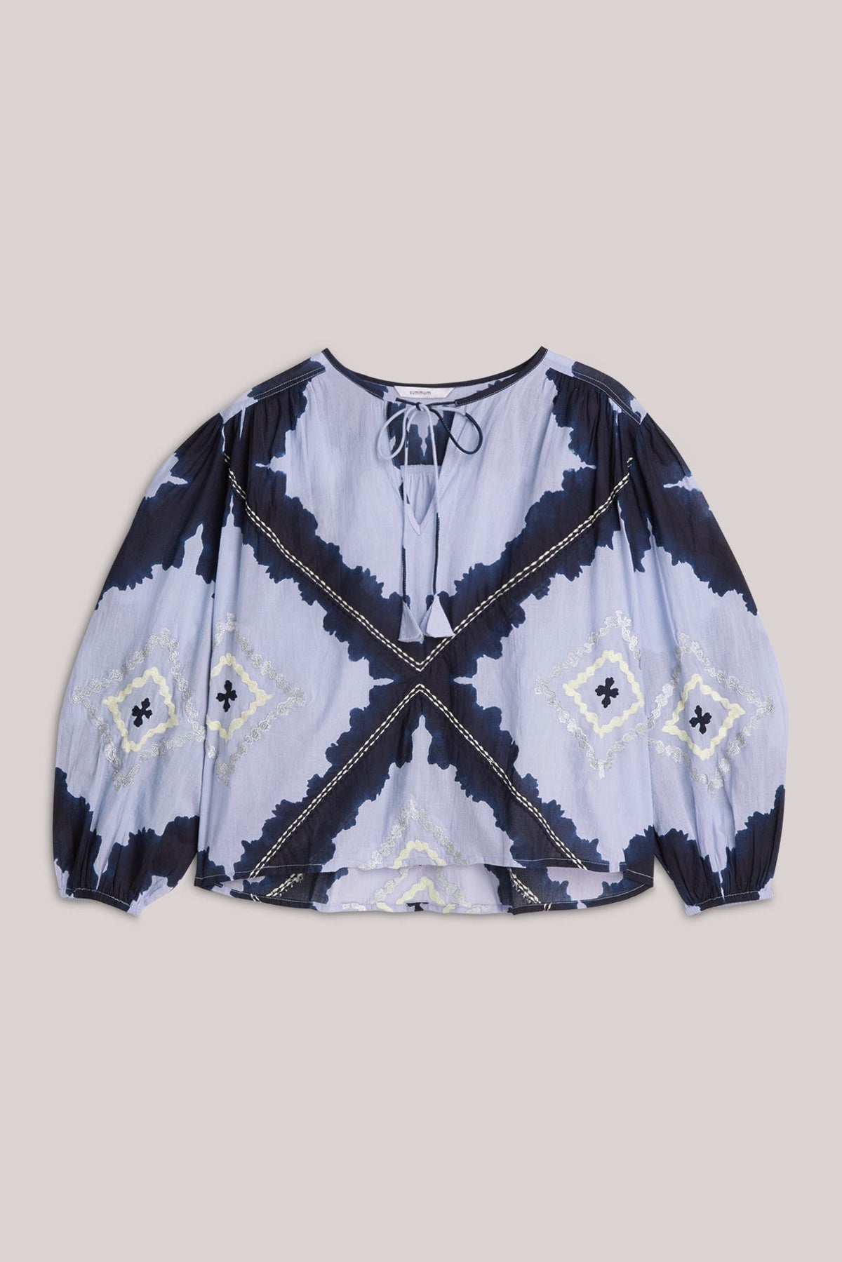 Embroidered blue blouse with a geometric pattern on a beige background