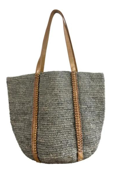 Woven handbag with brown leather trim on a white background