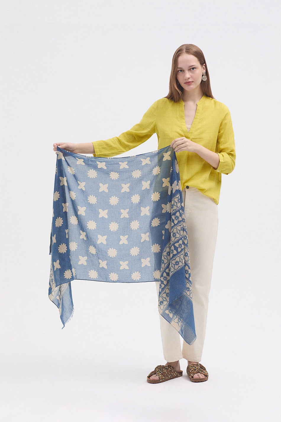 Woman holding a blue patterned scarf against a white background