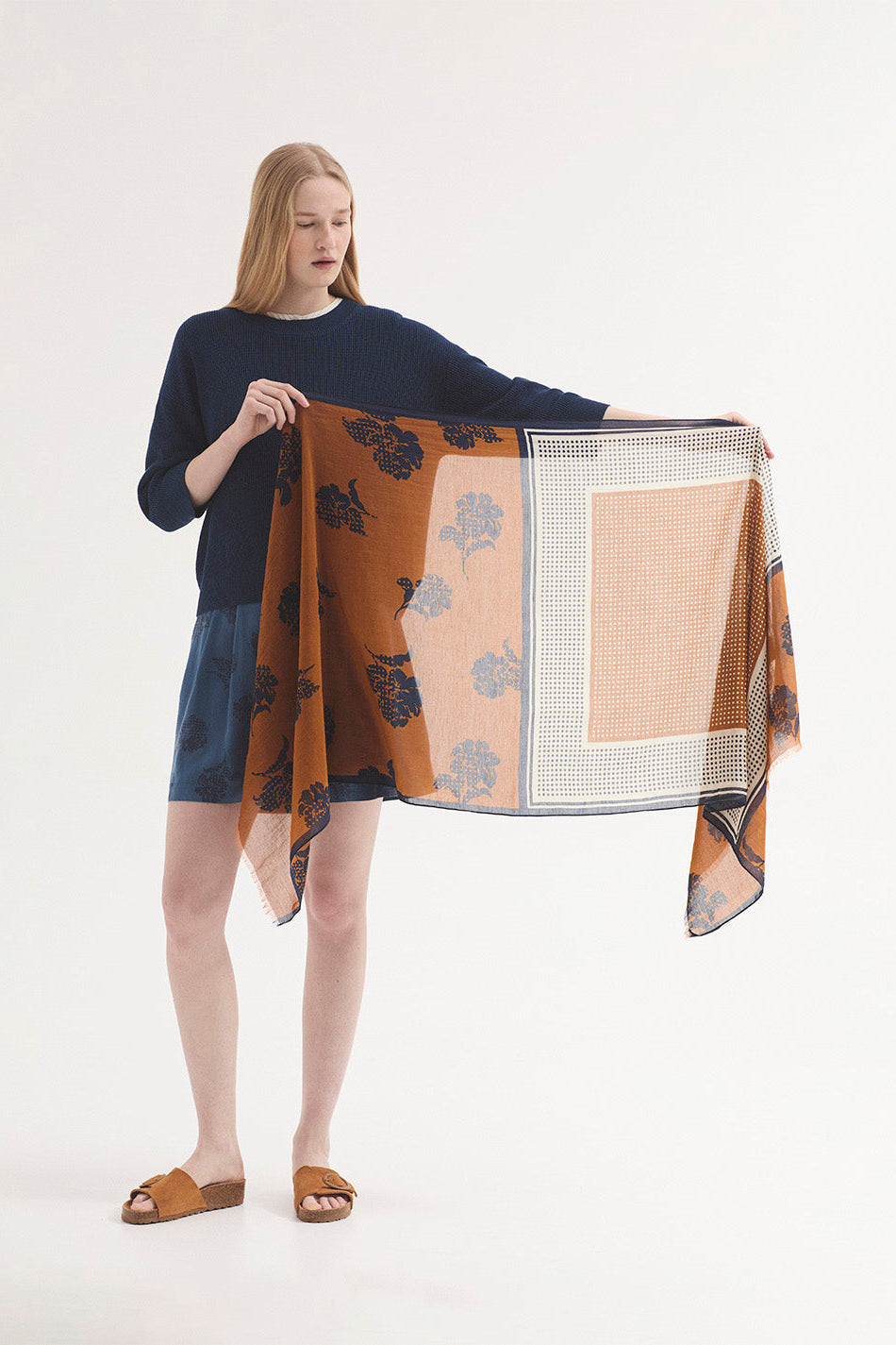 Woman holding a large, patterned fabric piece against a white background