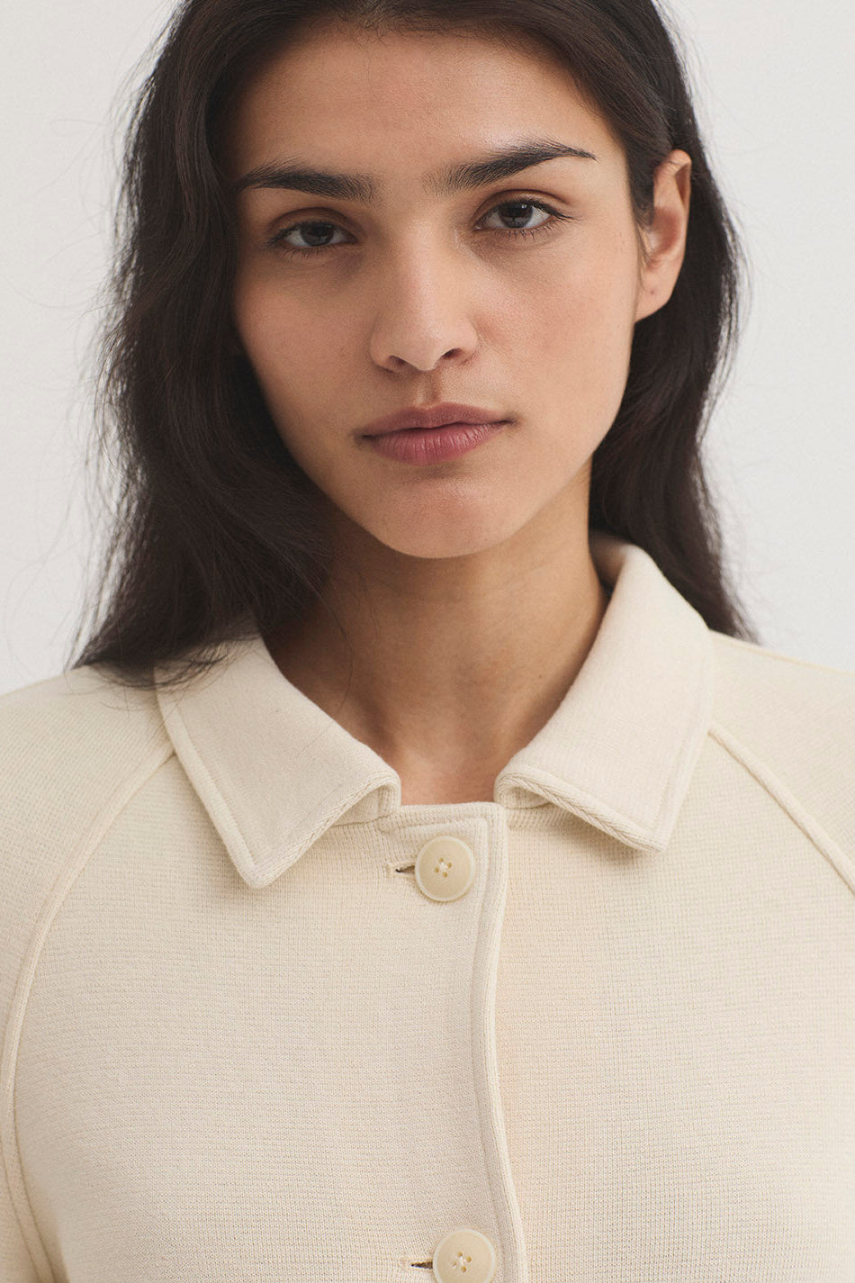Woman wearing a beige jacket with a plain background