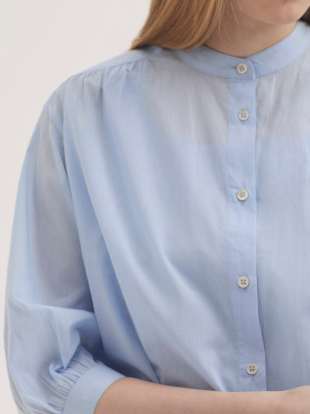 Light blue shirt with buttons worn by a person on a plain background