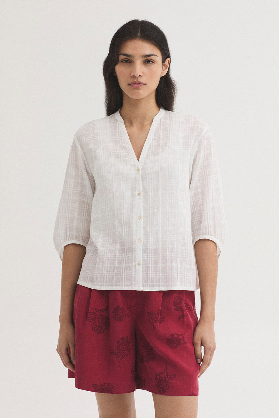 Woman wearing a white shirt and red shorts on a white background