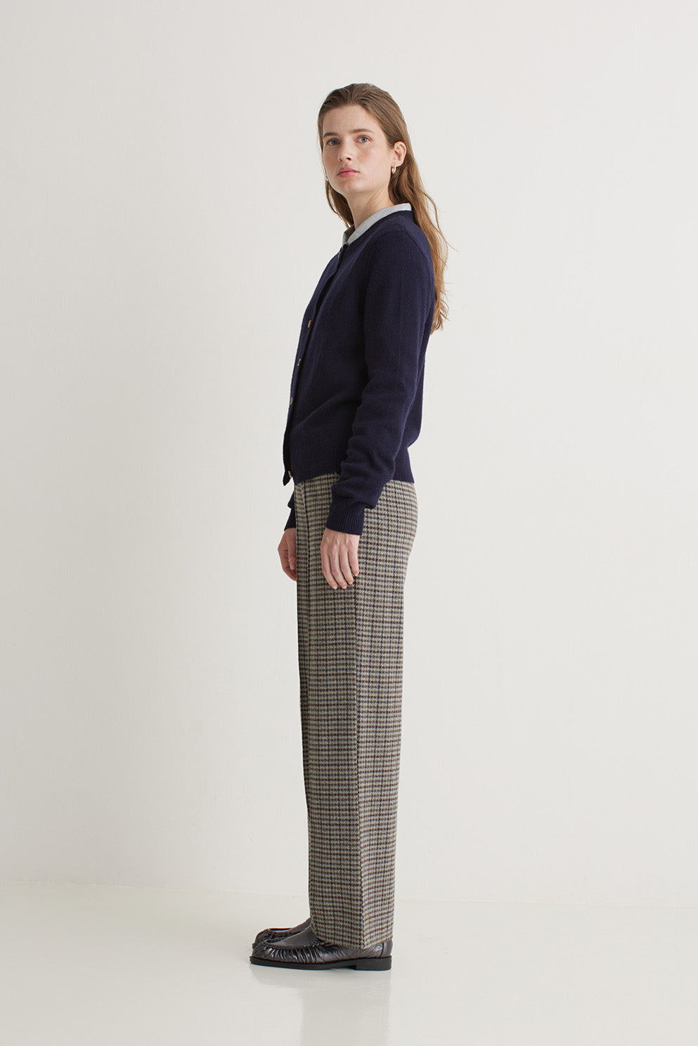 Woman wearing a navy sweater and checkered pants on a white background