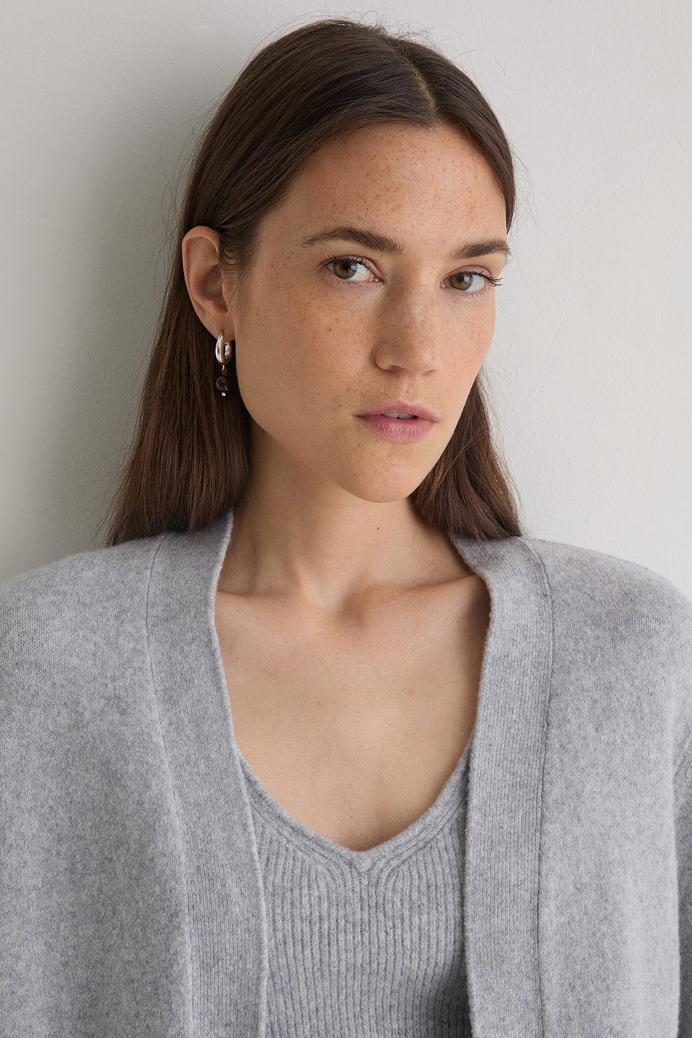 Woman wearing a gray cardigan against a plain background