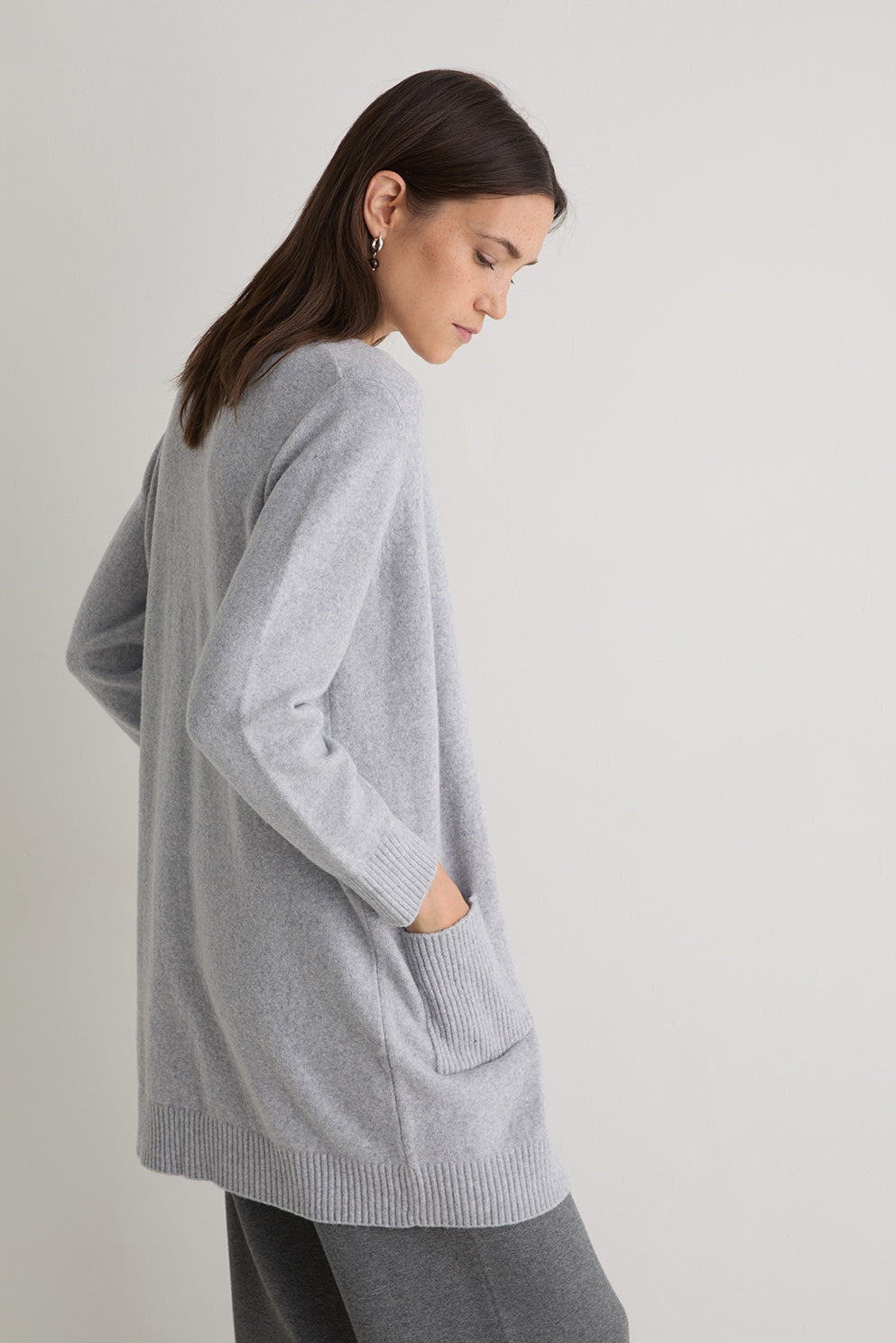 Woman wearing a gray cardigan on a light gray background
