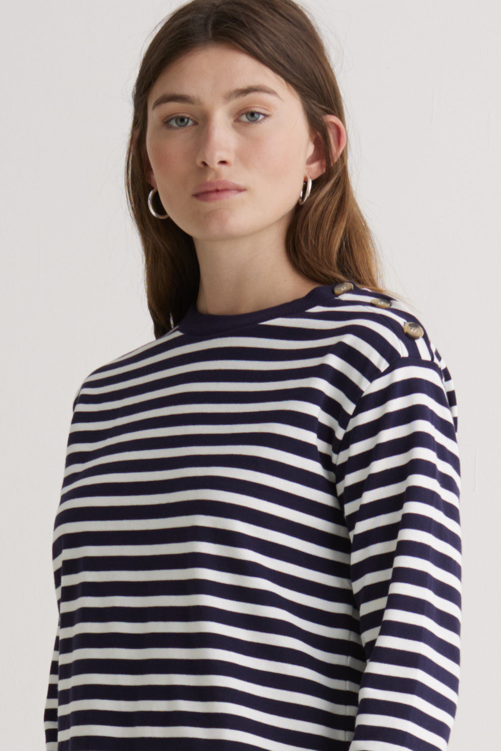 Woman wearing a navy and white striped long sleeve tee shirt  on a white background