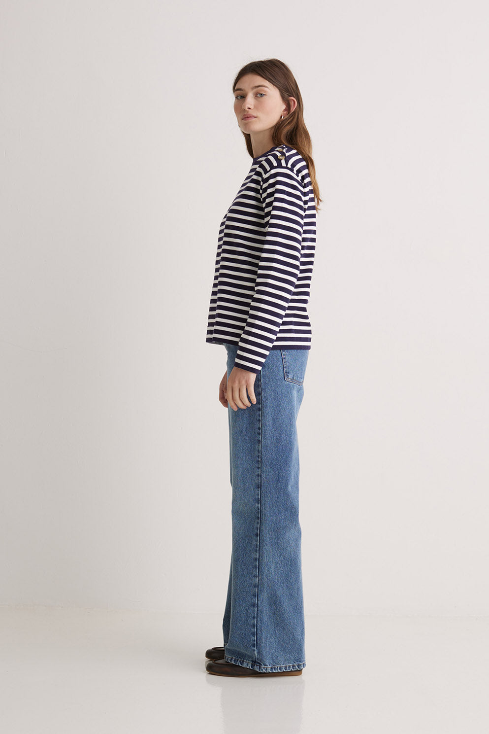 Woman wearing a navy and white striped long sleeve tee shirt  and blue jeans on a white background