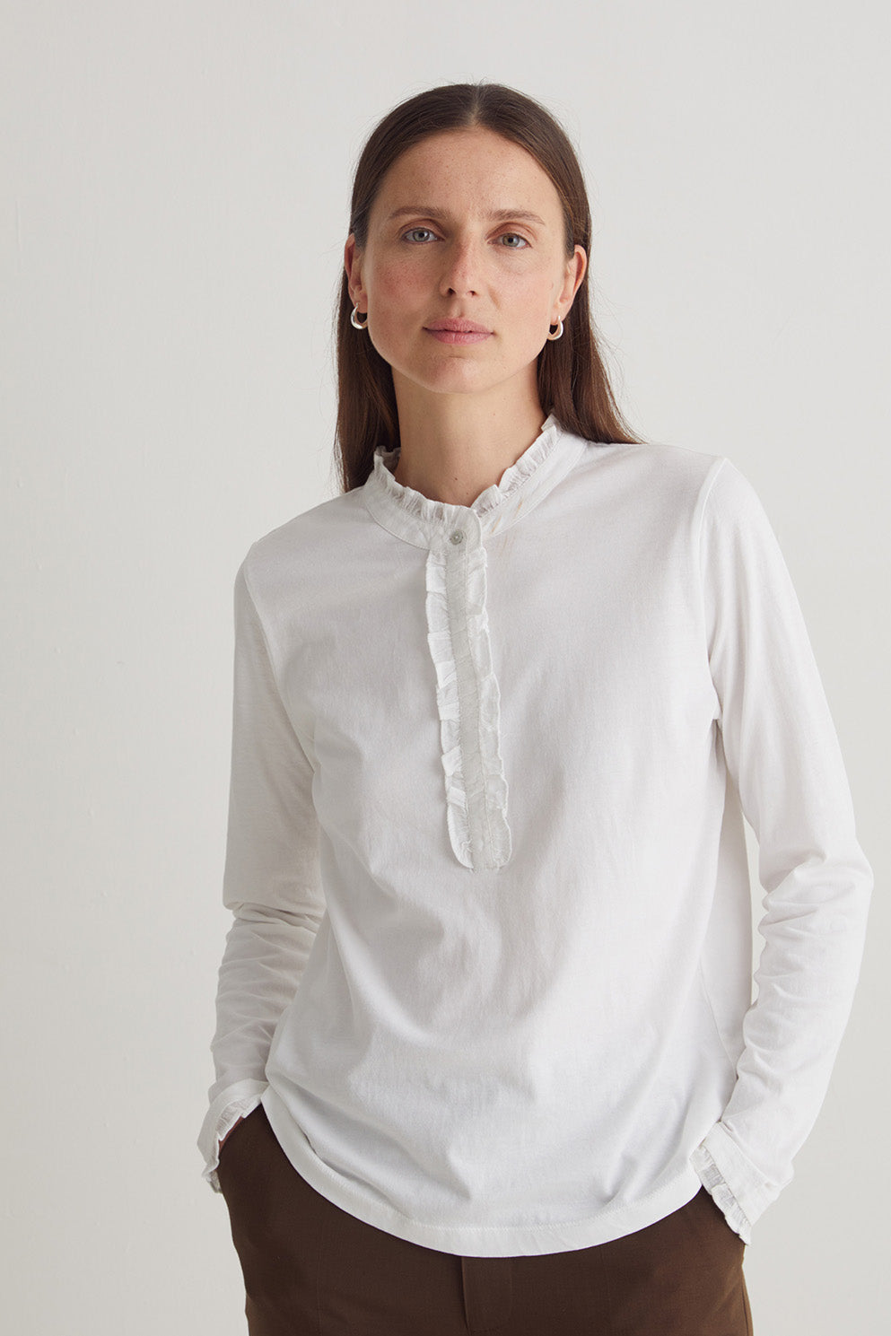Woman wearing a white blouse against a plain background