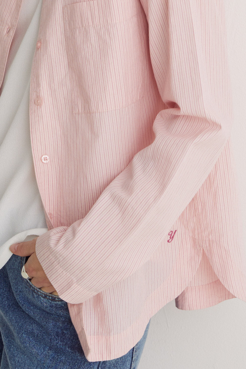 Close-up of a pink ribbed shirt with rolled-up sleeves on a light background