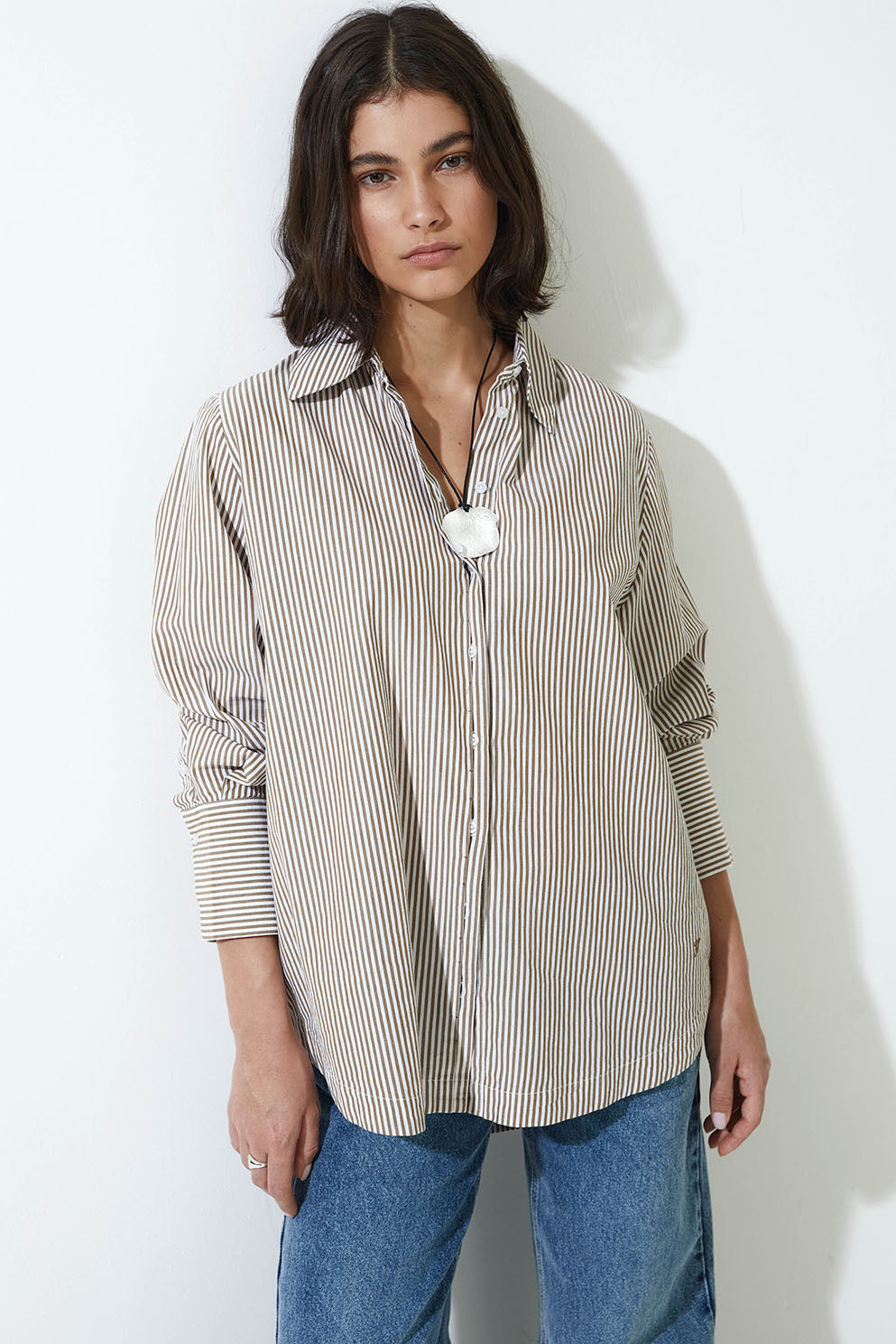 Woman wearing a striped shirt and jeans against a white background