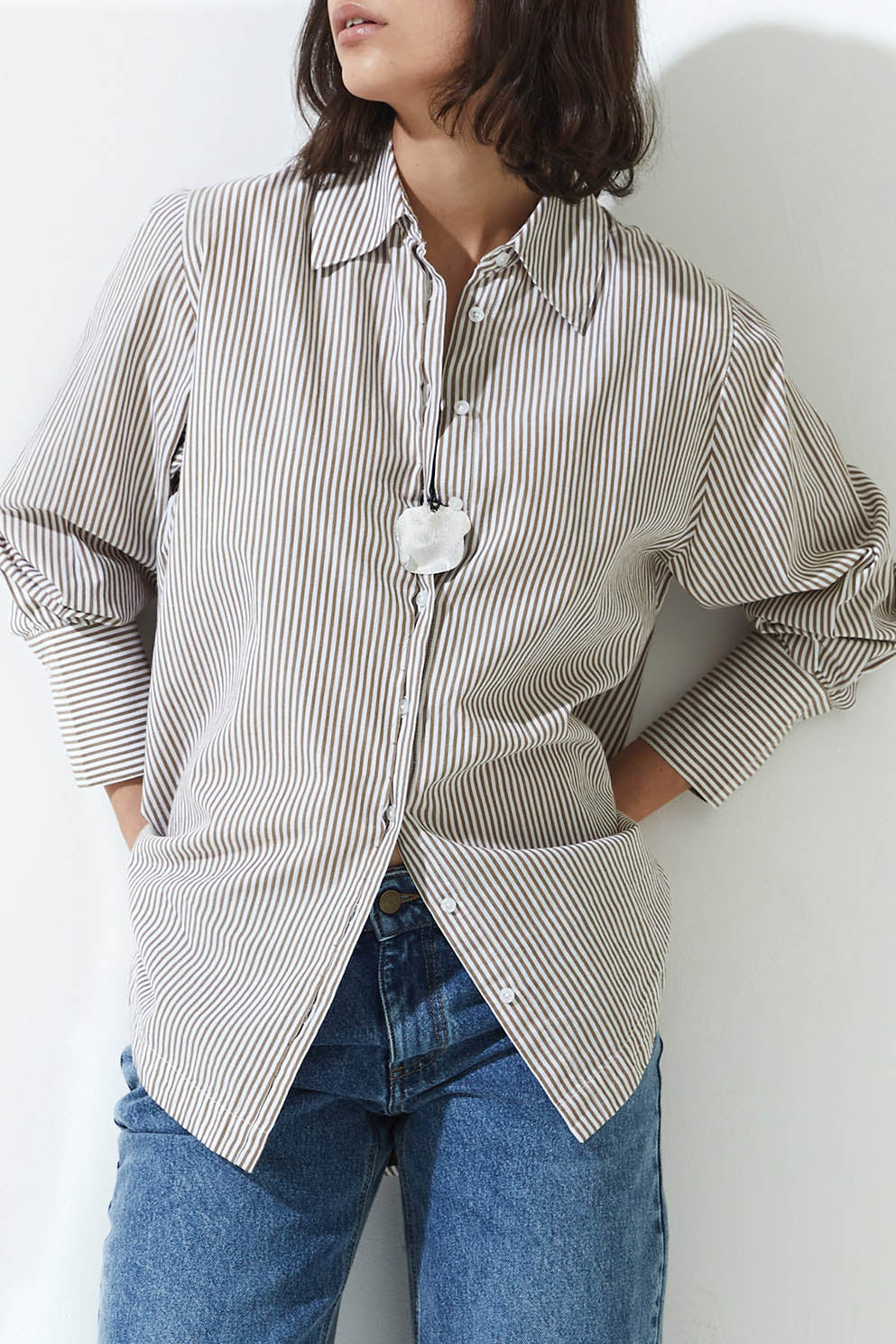 Person wearing a striped shirt and jeans against a white background