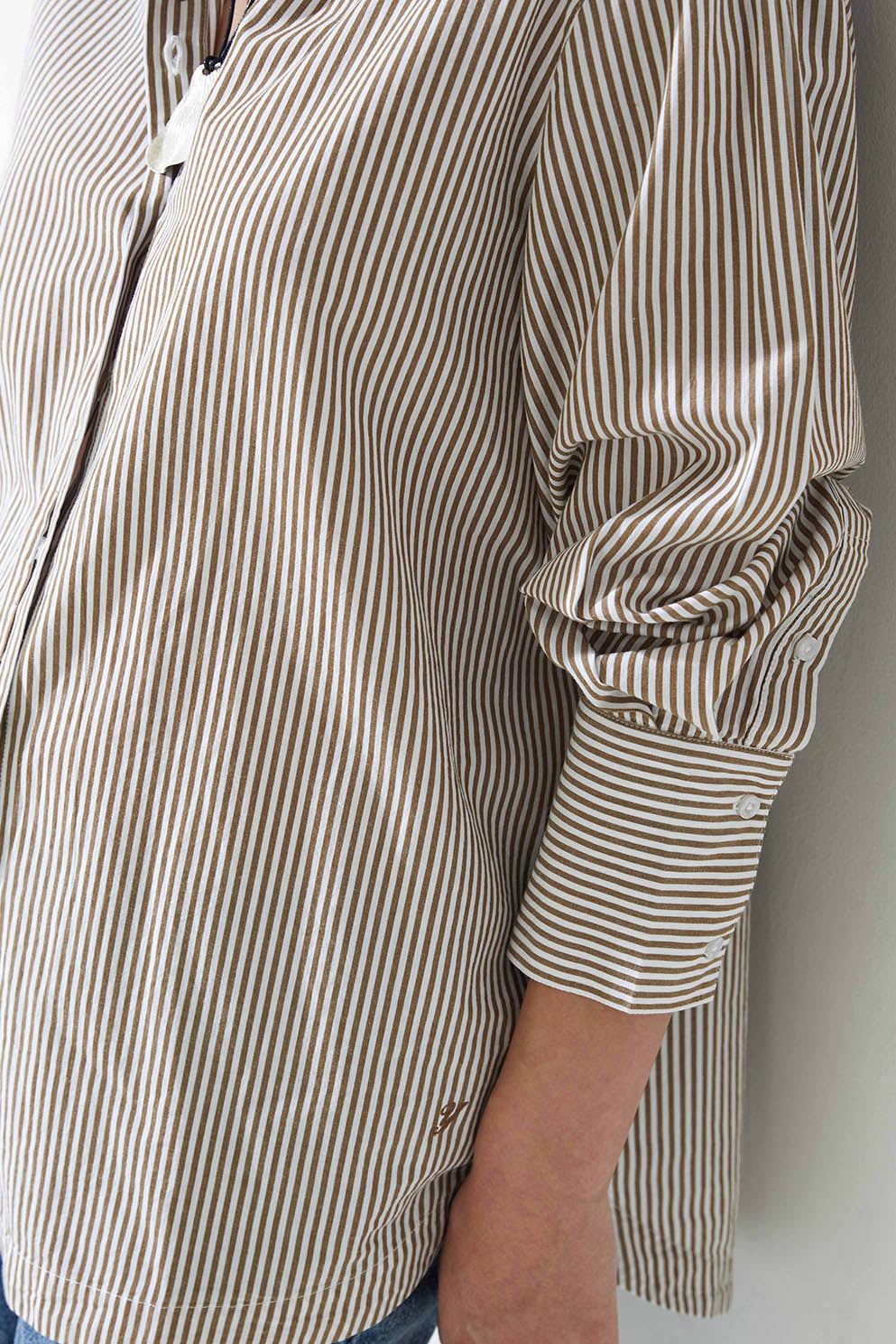 Person wearing a brown and white striped shirt against a plain background