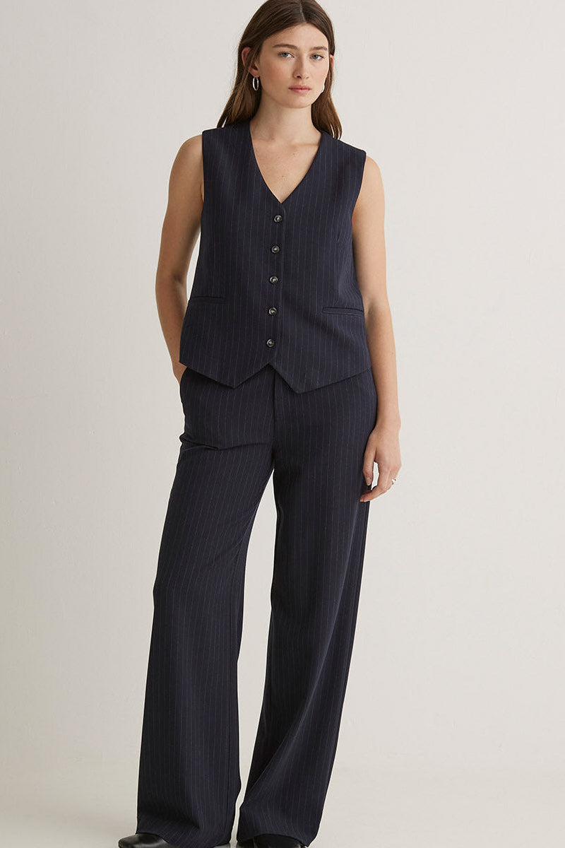 Woman wearing a navy  stripe vest and matching  wide-leg pants on a white background