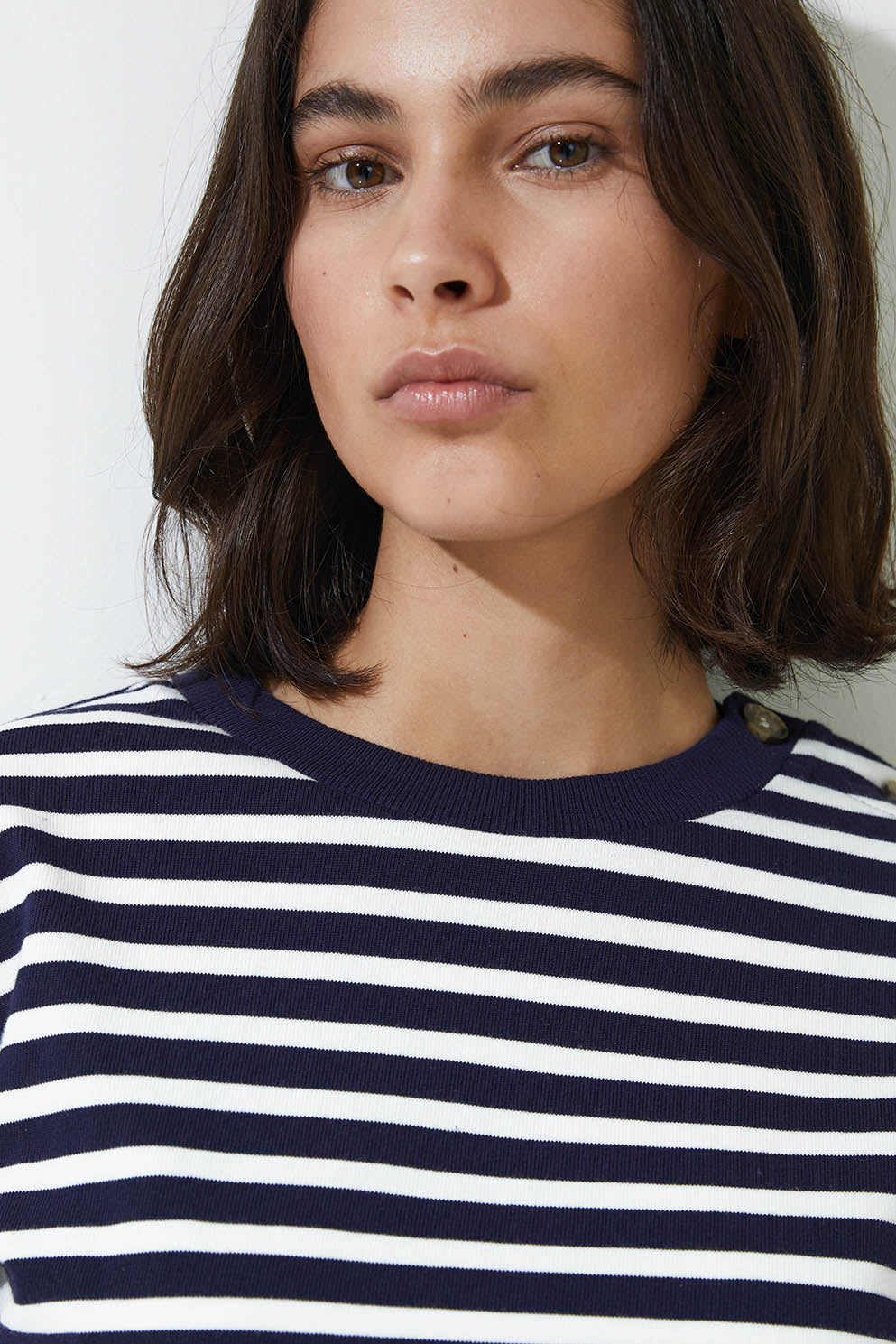 Woman wearing a navy and white striped long sleeve tee shirt  and blue jeans on a white background