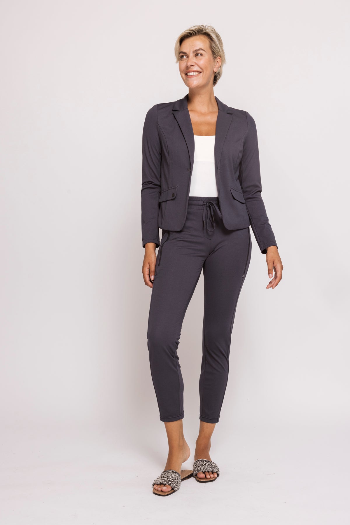 Woman wearing a dark gray suit with a white top on a light gray background