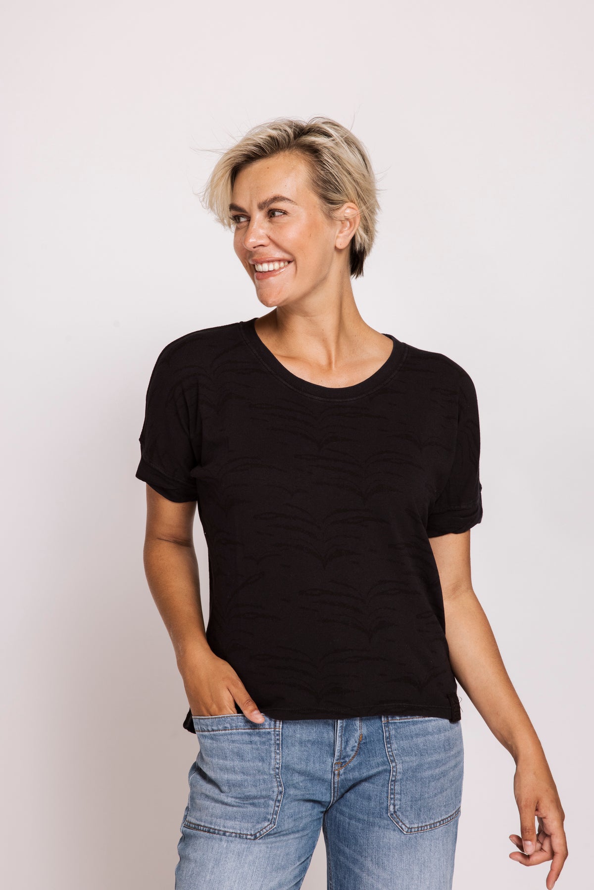 Woman wearing a black t-shirt and blue jeans against a white background