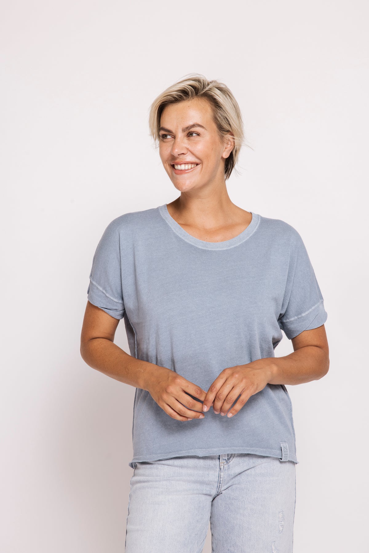 Woman wearing a light blue t-shirt and jeans on a white background