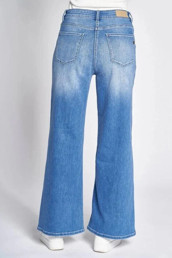Blue wide leg denim jeans on model with white sneakers on white background 