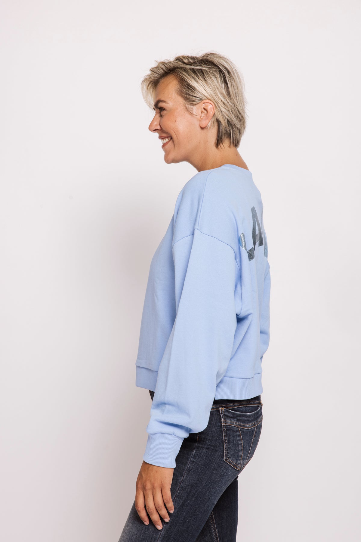 Person wearing a light blue sweatshirt with text on a plain background
