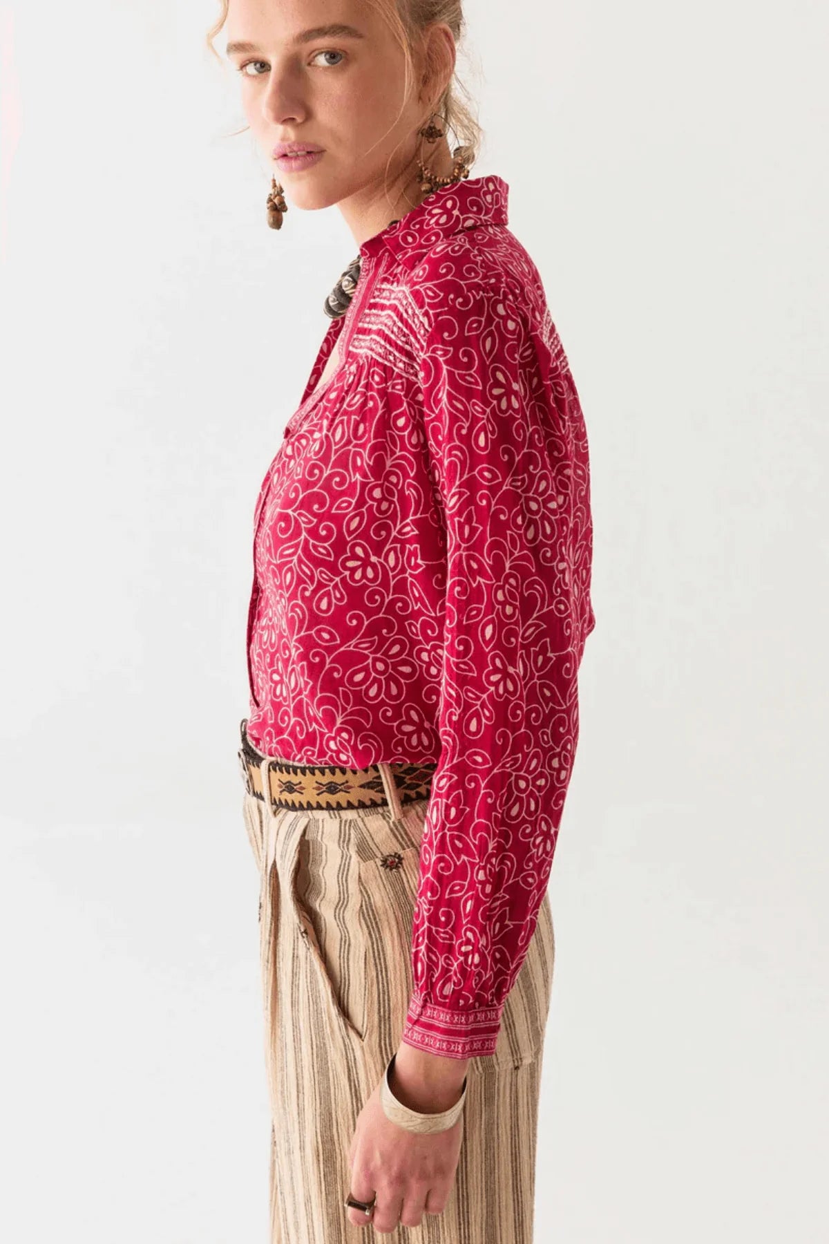 Person wearing a red and white floral patterned shirt with a white background