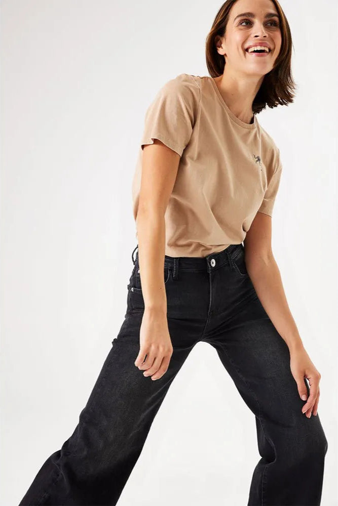 Woman wearing a beige t-shirt and black jeans on a white background