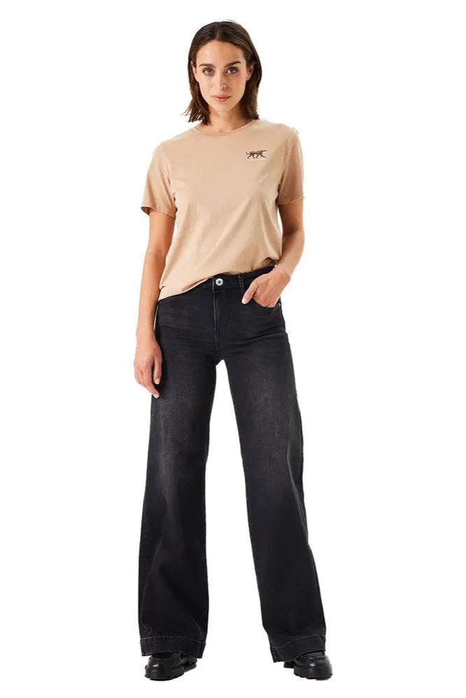 Woman wearing a beige t-shirt and black jeans on a white background