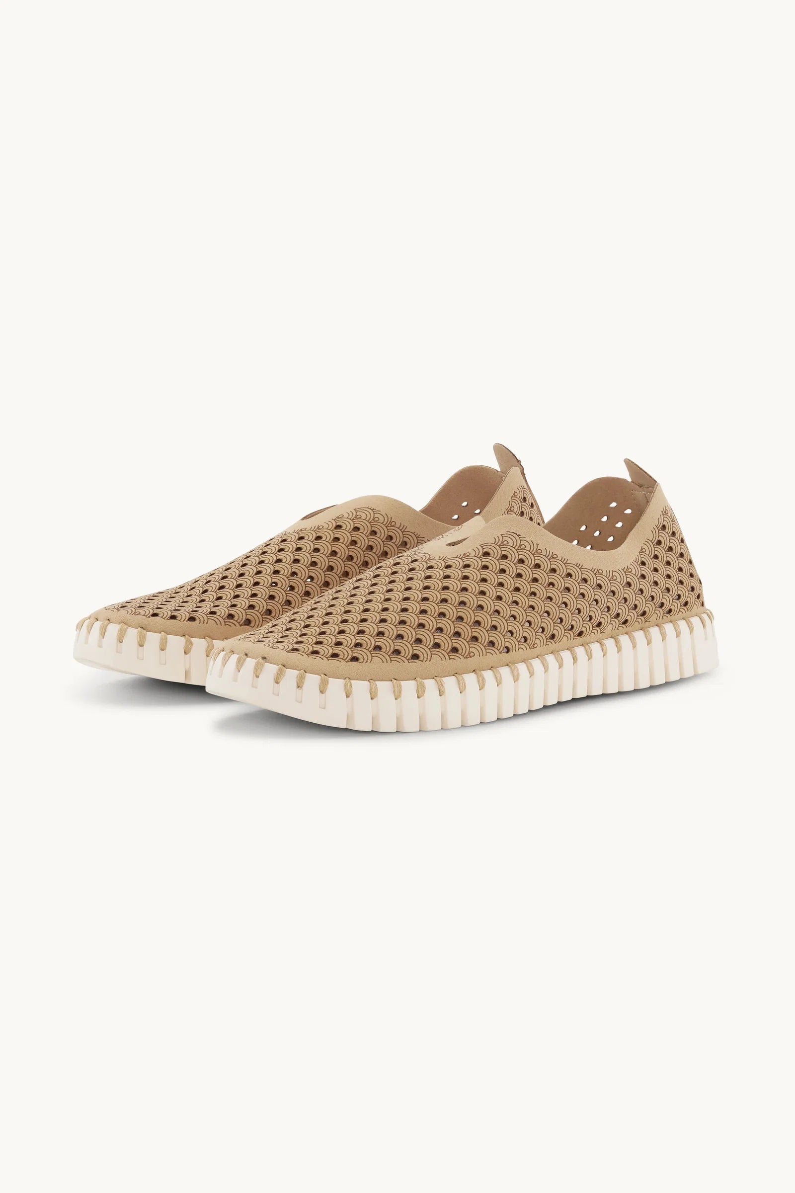 Pair of beige slip-on shoes with white sole on a white background