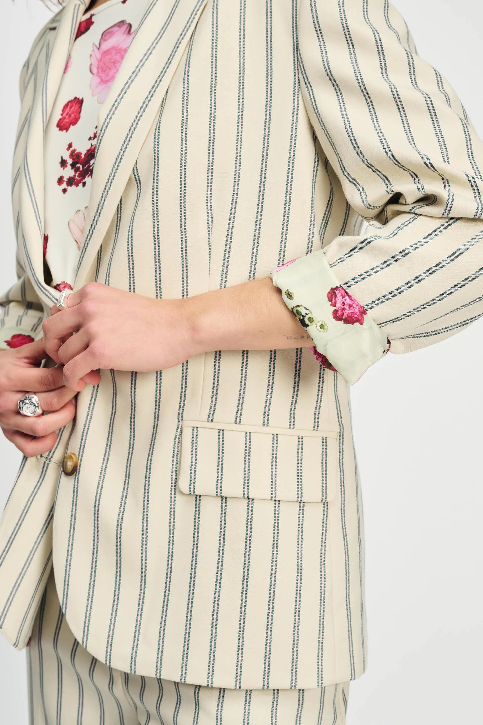 Close-up of a person wearing a striped suit with floral patterns on a white background