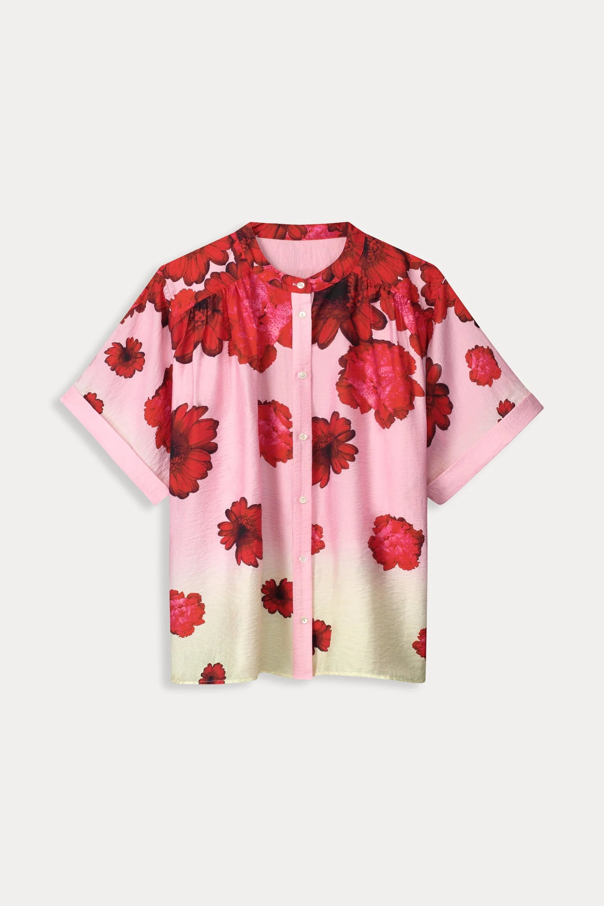 Woman wearing a pink floral short sleeve blouse and cream pants on a white background 