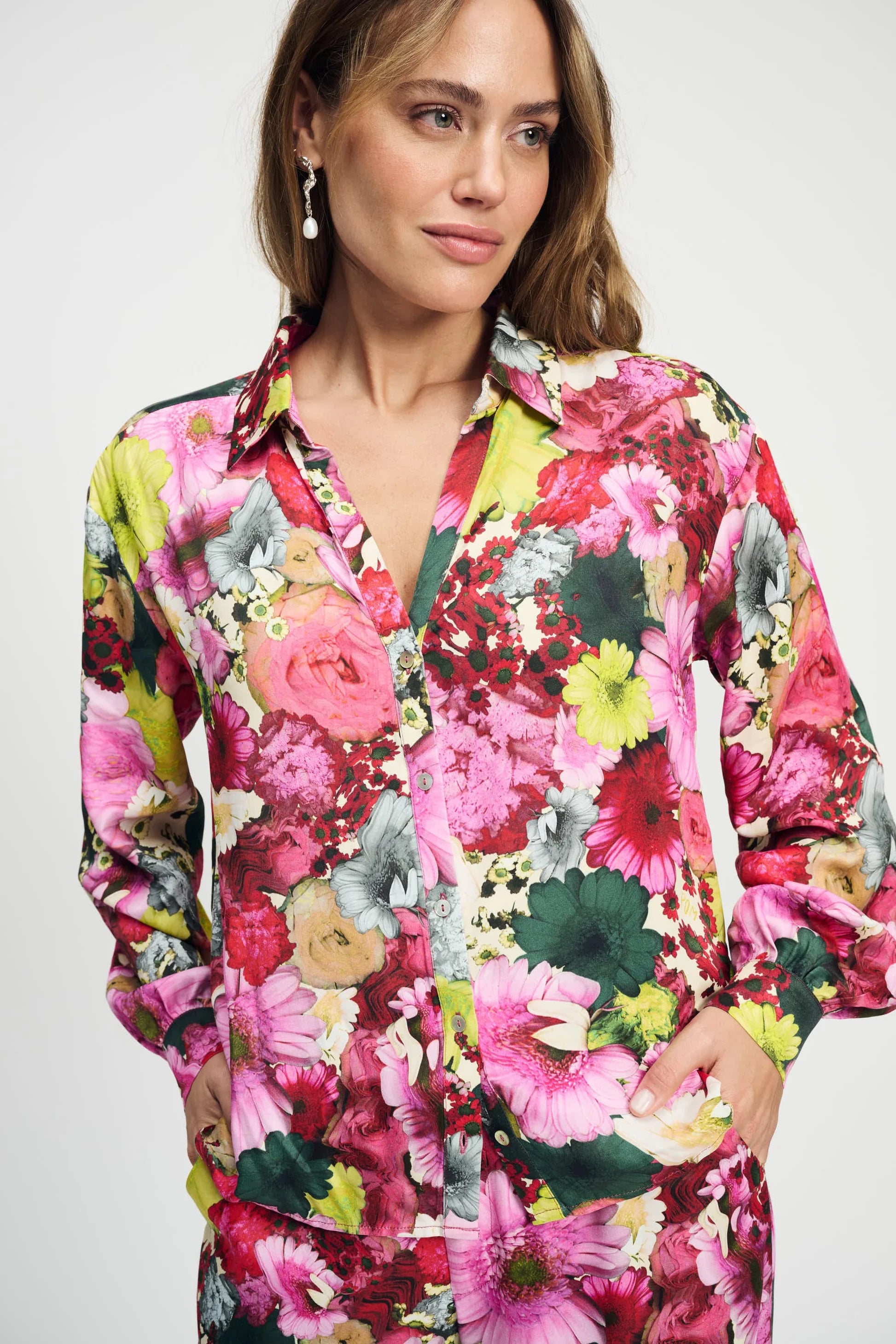 Model wearing a long sleeve bright floral blouse and matching pant on a plain background